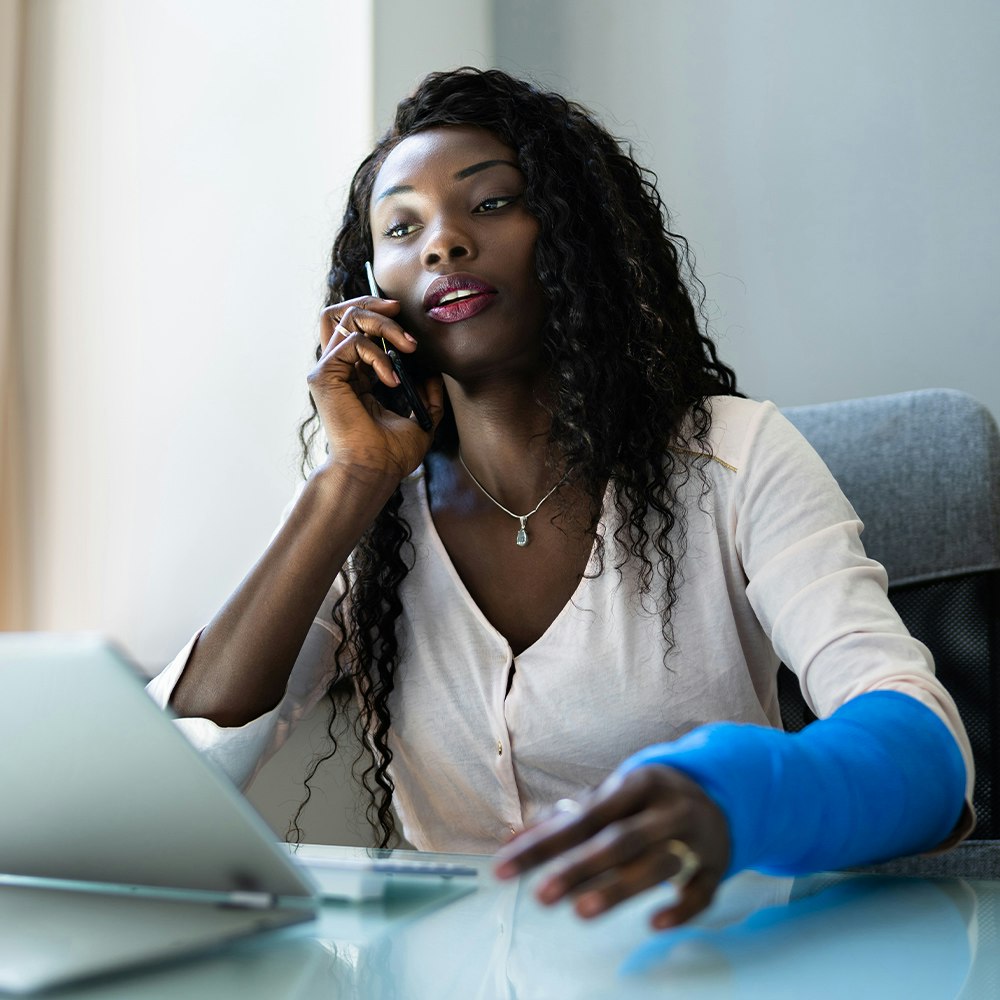 Injured worker on the computer and phone as she works on a social security disability claim