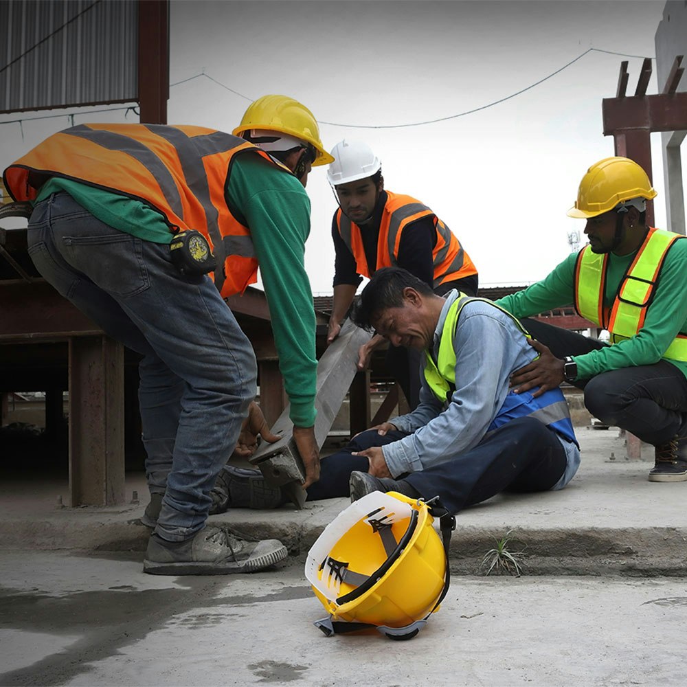 Construction workers helping injured co-worker who is trapped underneath a beam