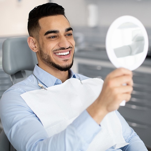 Smile makeover patient looking at results with a hand mirror