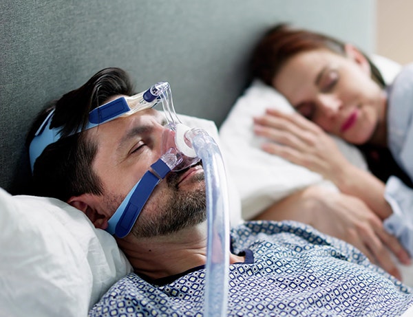 Couple sleeping peacefully as man wears a CPAP