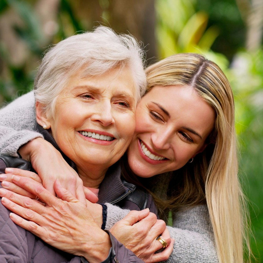 Adult woman hugging mother in a wheelchair
