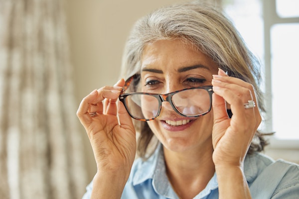 Smiling lady putting on glasses
