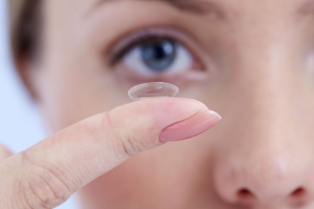 Photo of a woman holding a contact lens