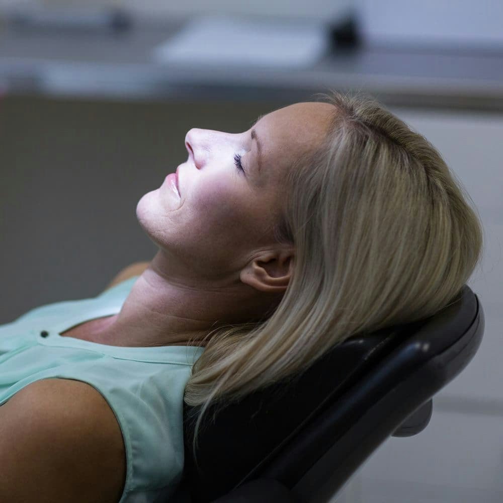 Woman lying in dental chair with eyes closed