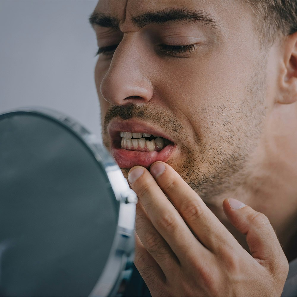 Man examining tooth in mirror