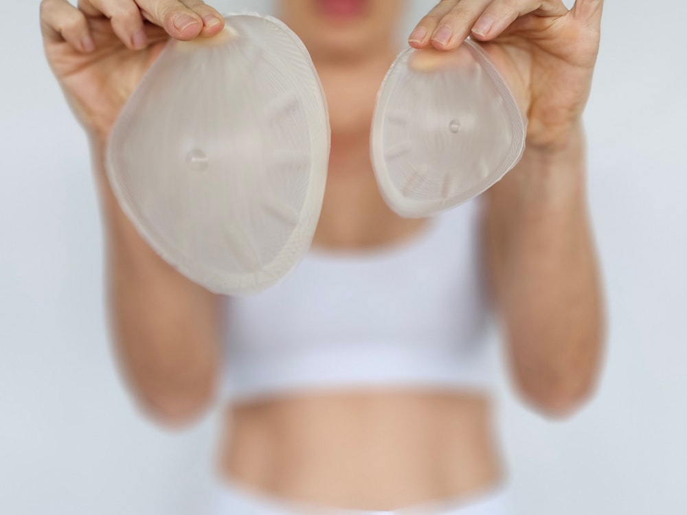 Hands holding two breast implant sizers of different sizes