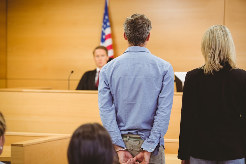 Man in handcuffs standing before judge in court