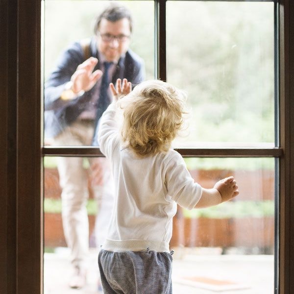 Father waving goodbye to baby through a window