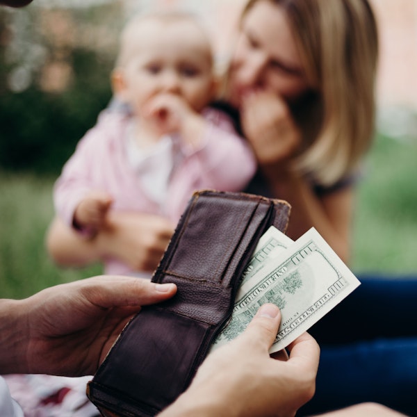 Person taking money from wallet, with baby and woman in the background