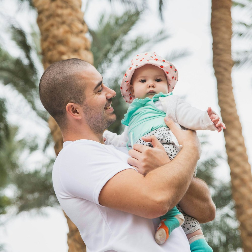 Father holding baby with palm trees in the background
