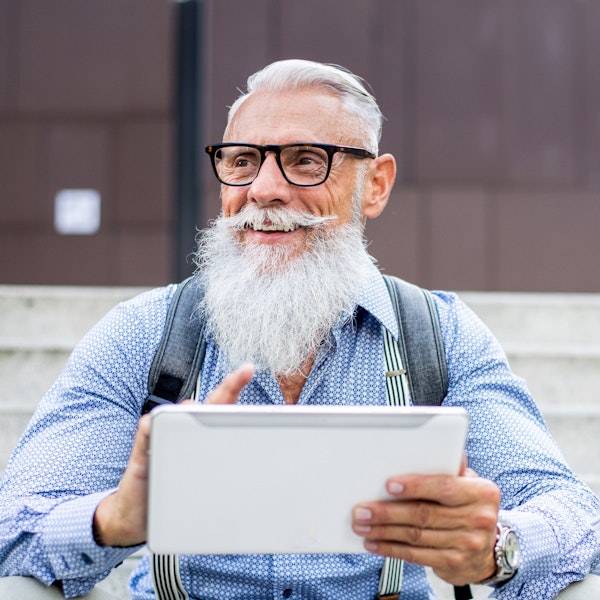 Mature man smiling while looking at pensions on tablet