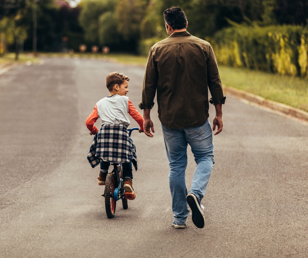 Father walking and watching son bike