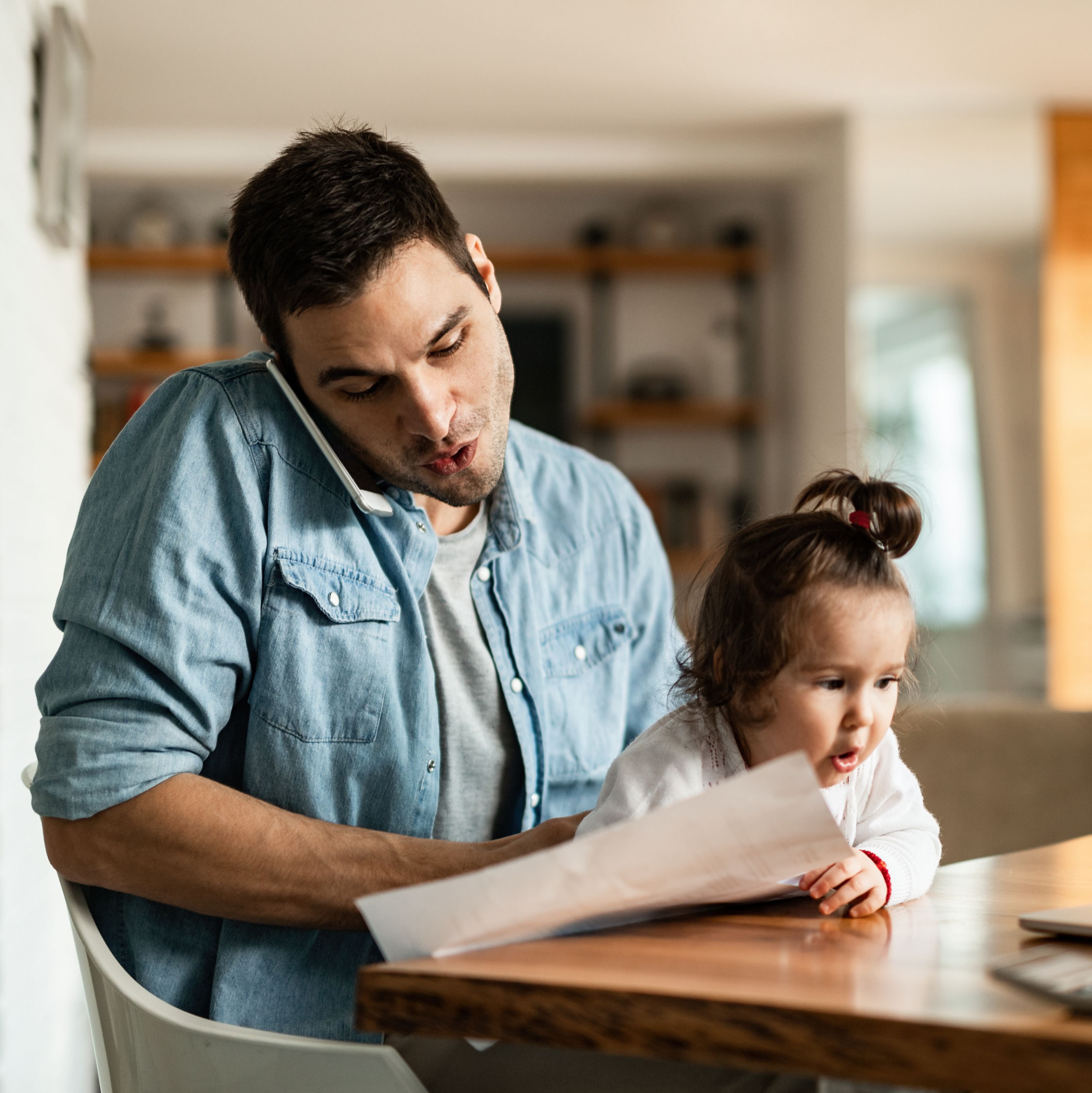 Father on phone and laptop with baby in lap
