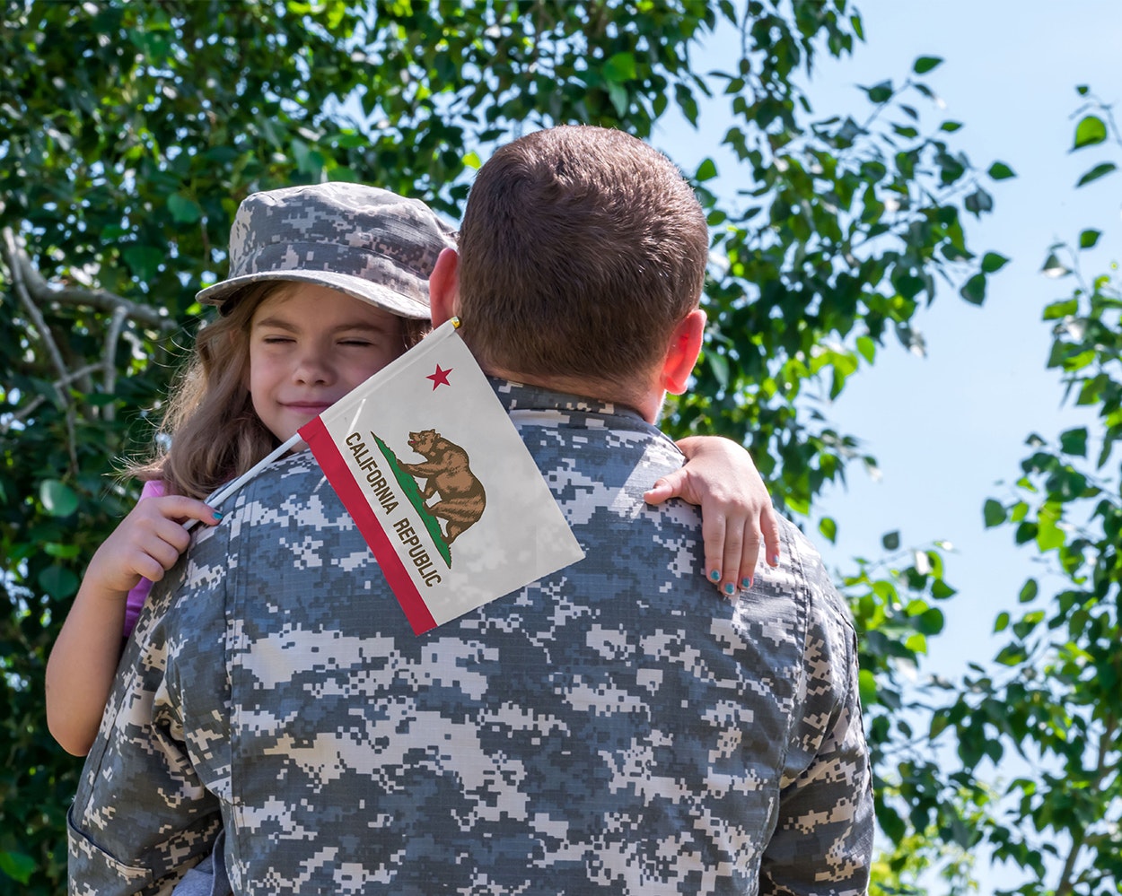 Military dad carrying his daughter, who is holding a California flag