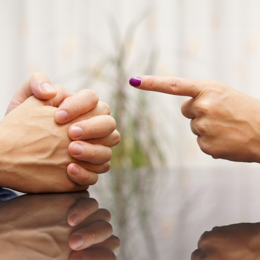 Woman's hand pointing a man's clasped hand