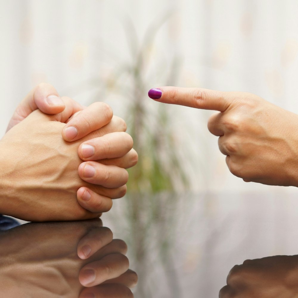 Woman's hand pointing a man's clasped hand