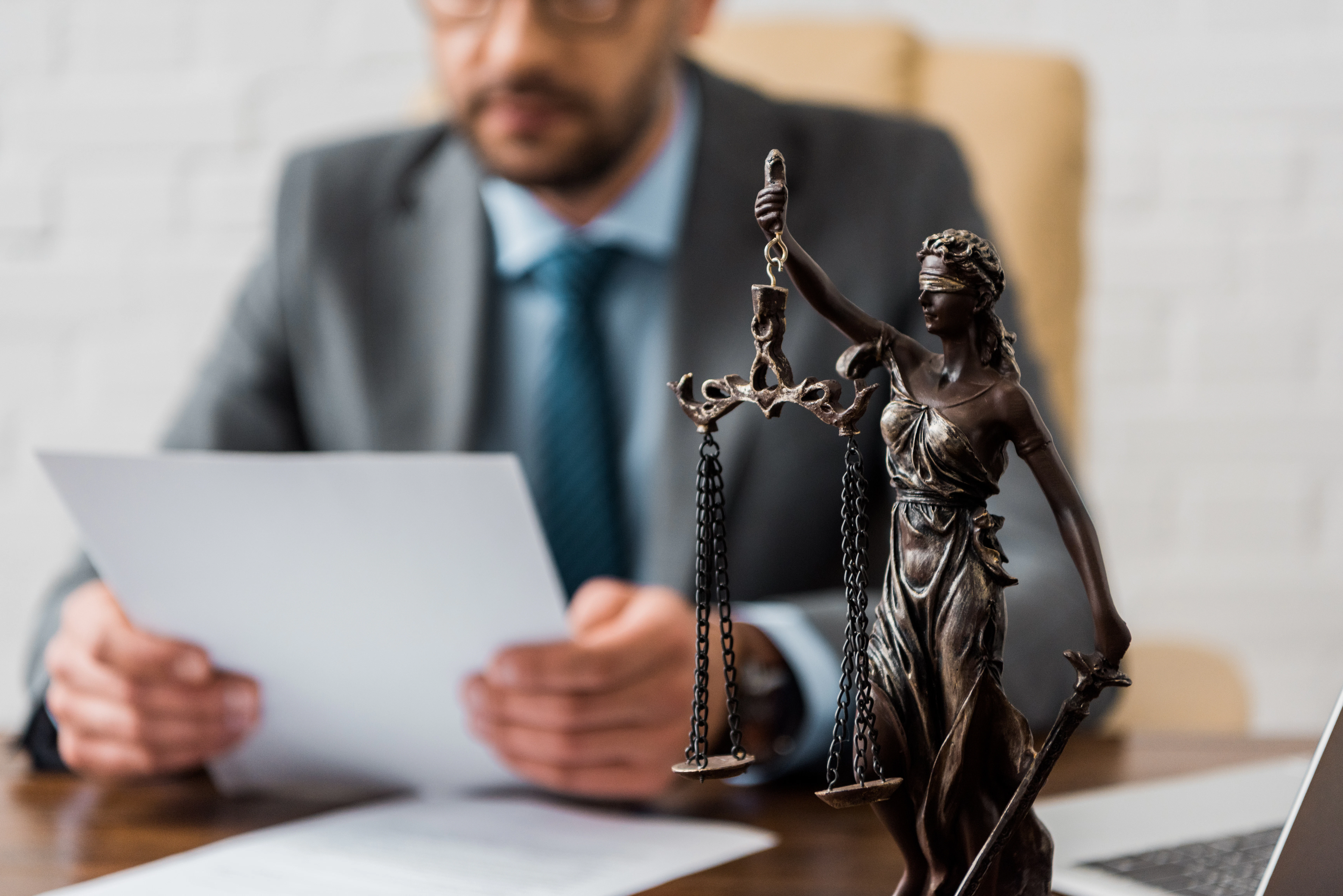 Lady Justice with an attorney in the background reviewing contract