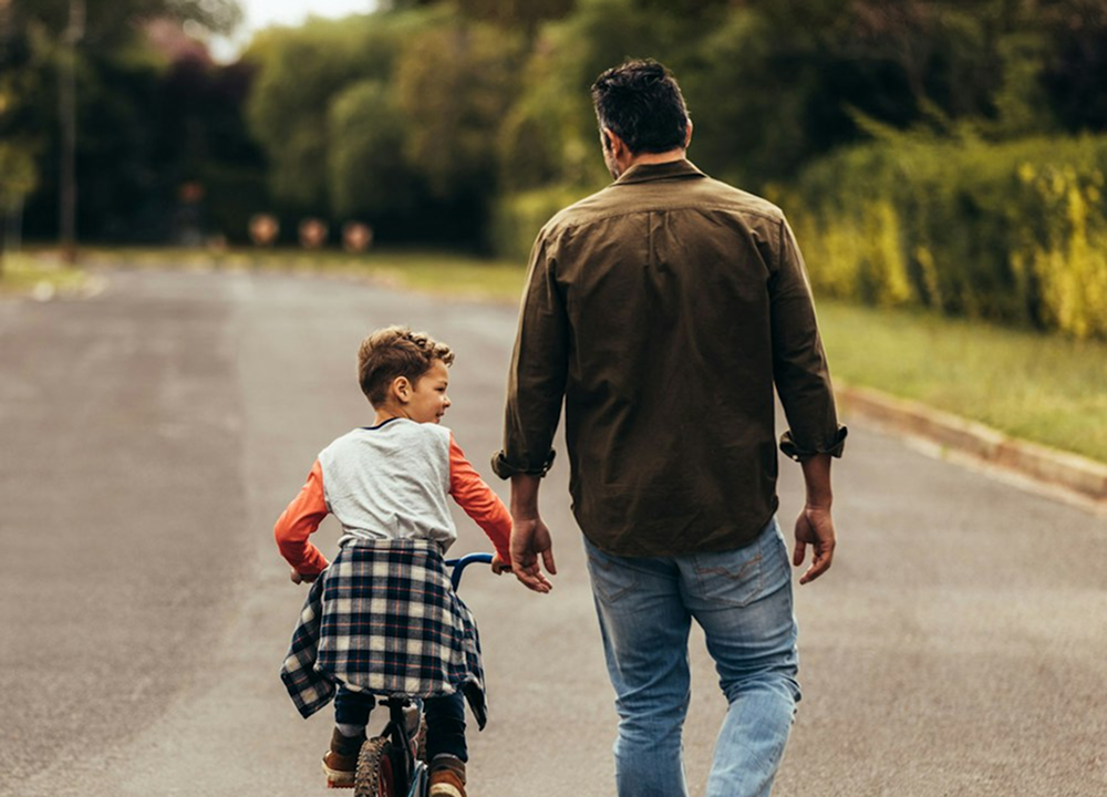 Father walking and watching son bike