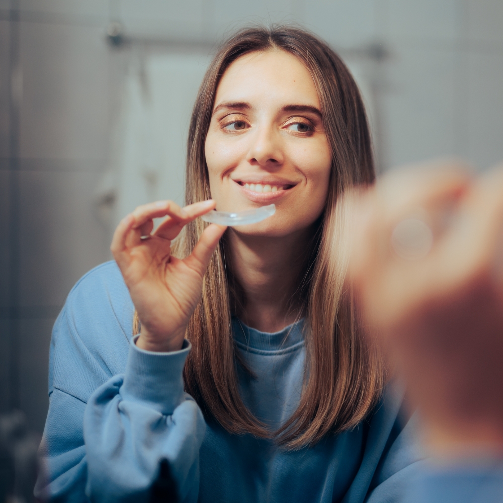 Woman holding retainers in front of mirror