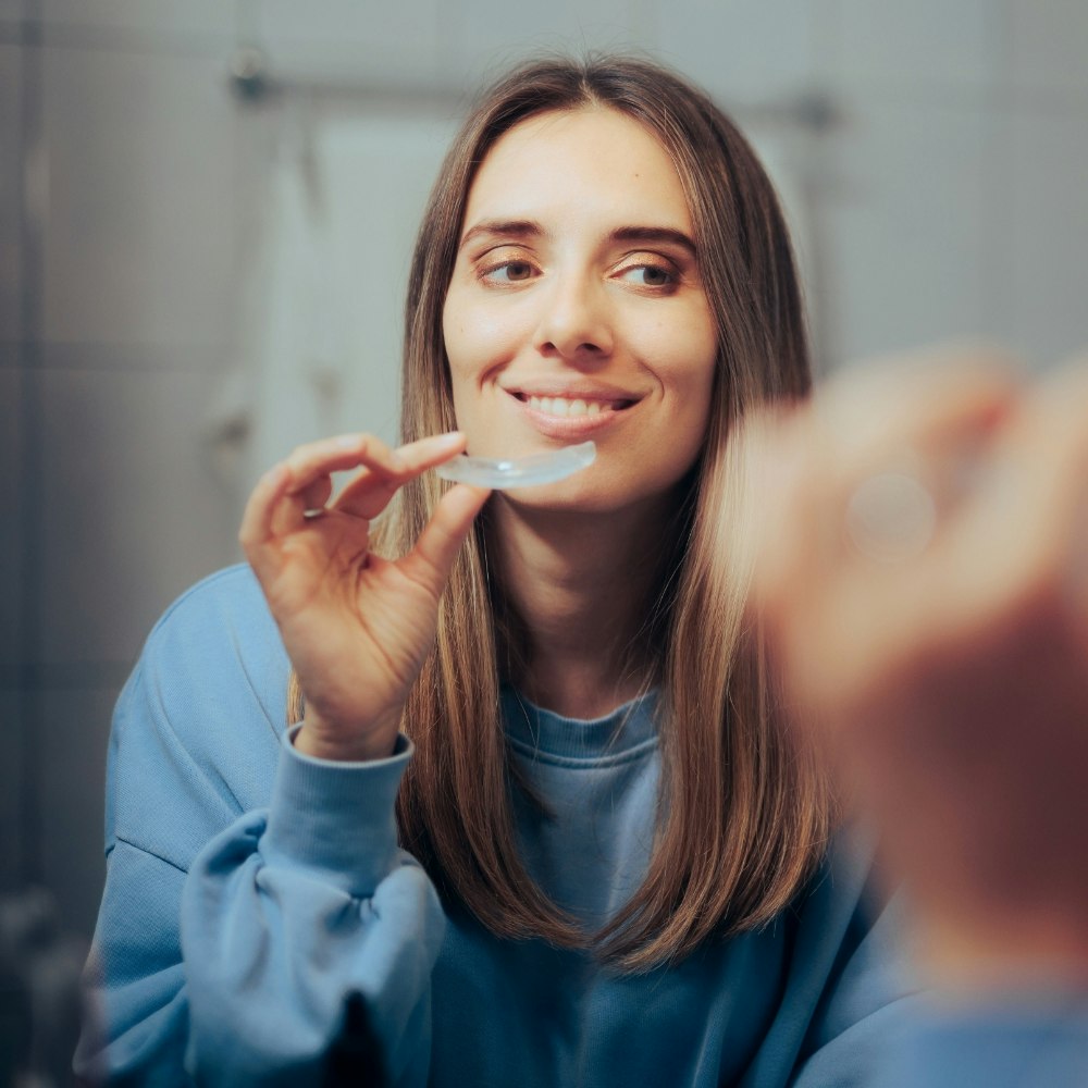 Woman holding retainers in front of mirror