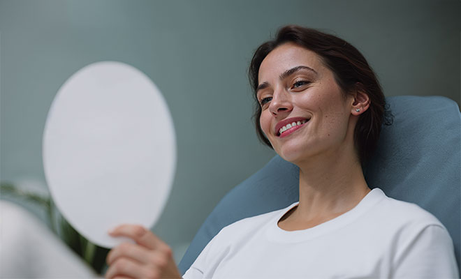 Woman smiling in mirror at the dentist