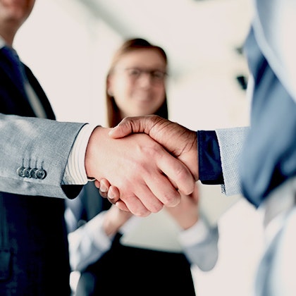Two men shaking hands, with a woman in the background
