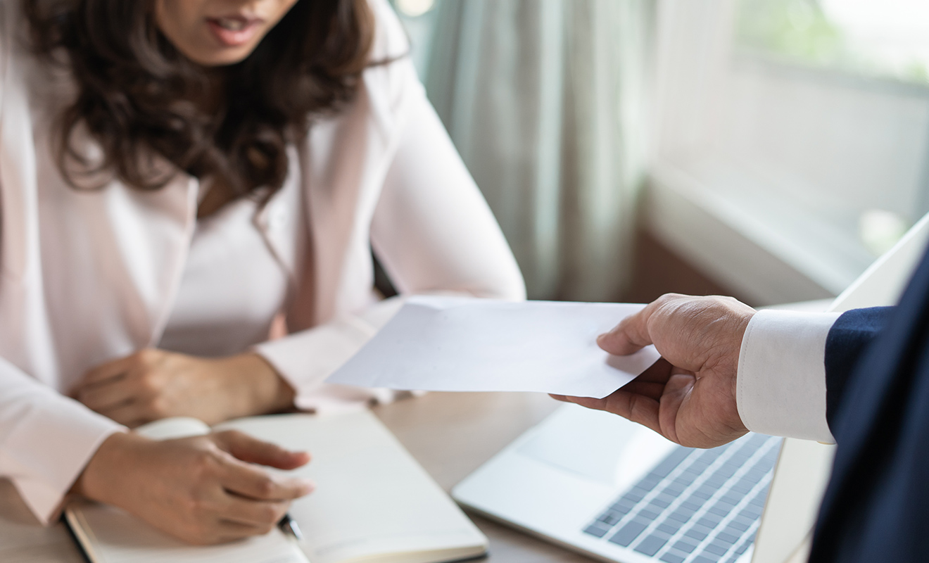 woman receiving paycheck from male manager