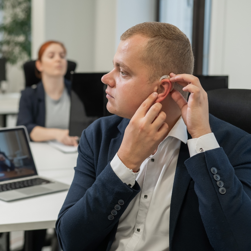 Man at work putting on hearing aids