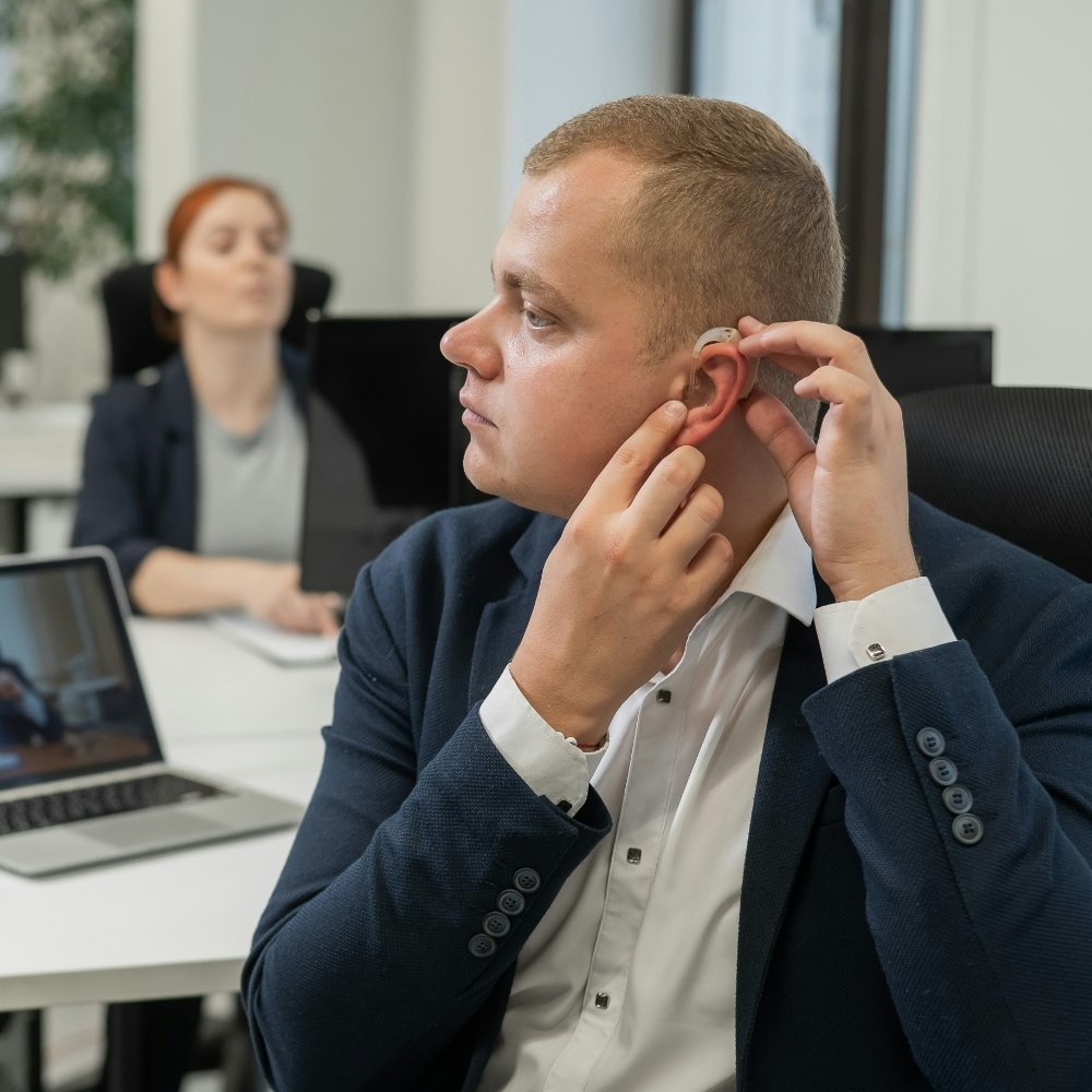 Man at work putting on hearing aids