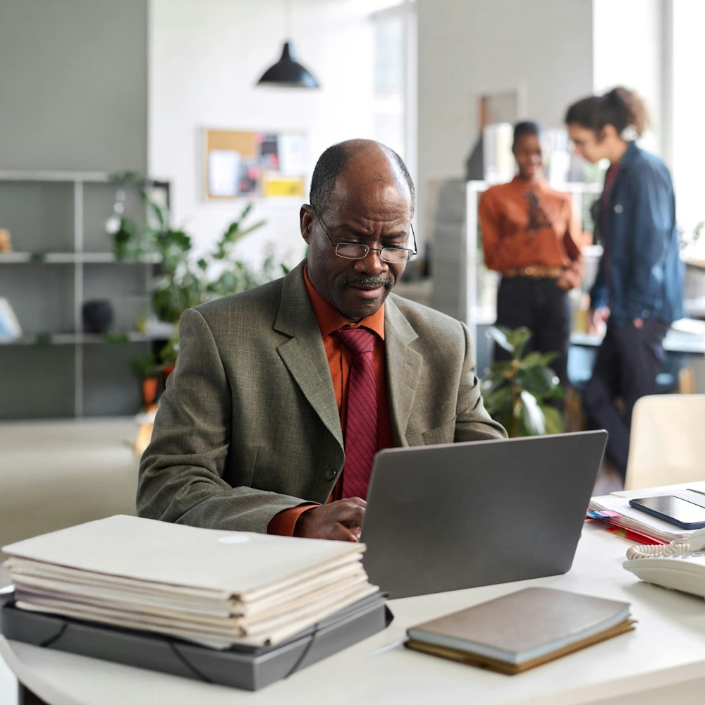 man working on his laptop with coworkers in the background