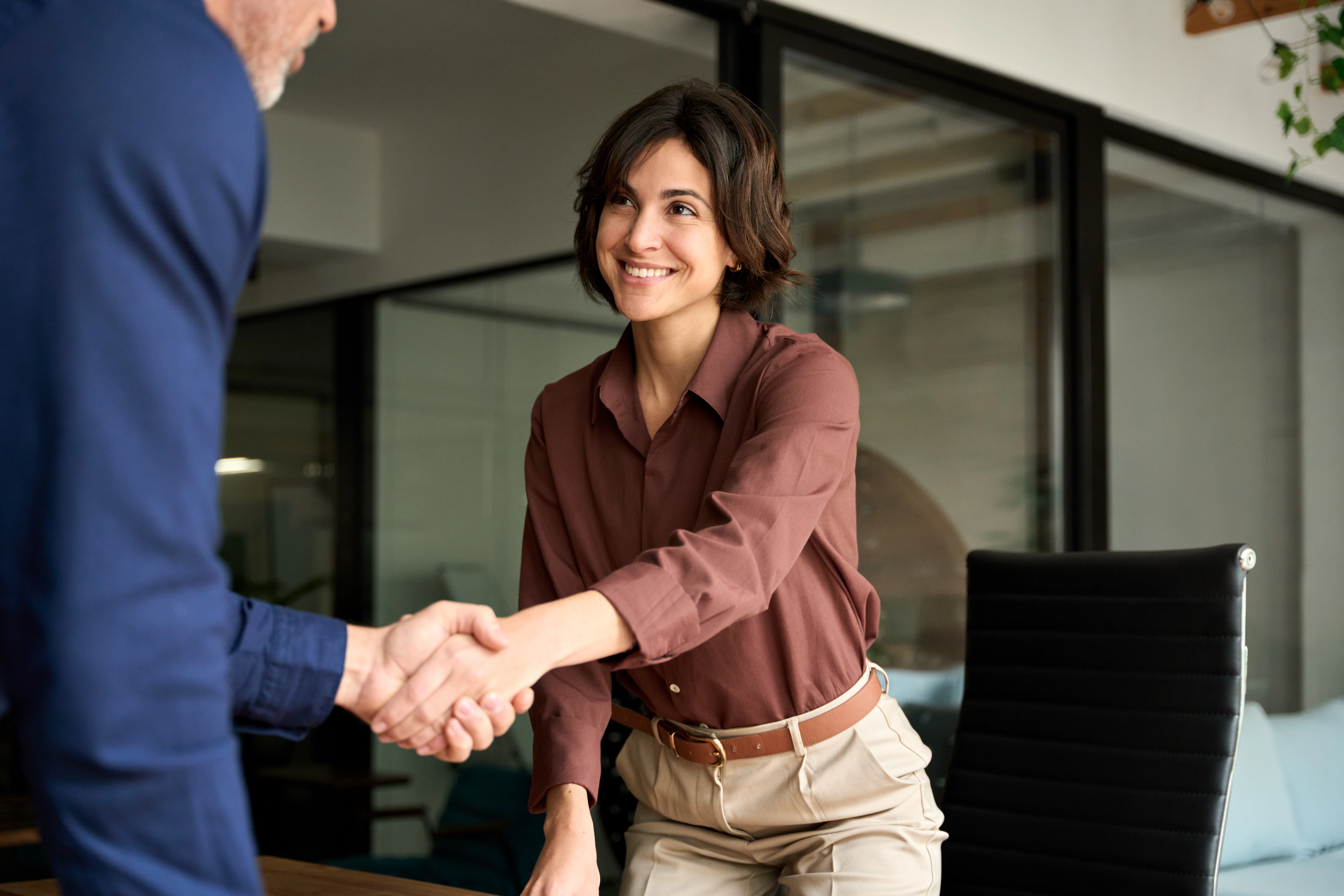 woman smiling shaking hands w/ a man