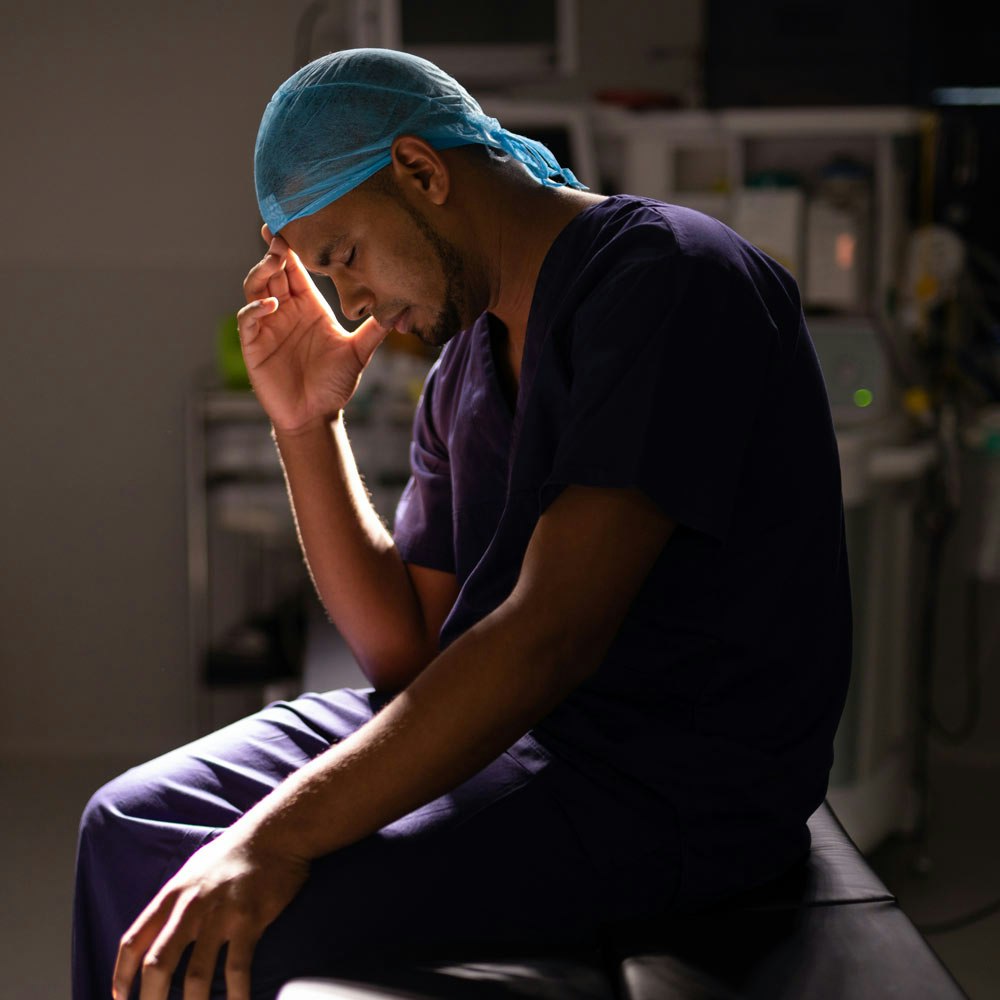 Doctor's head in hands in a dark medical room