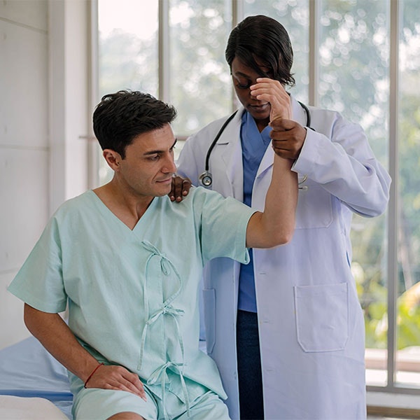 Man in hospital having arm stretched by doctor