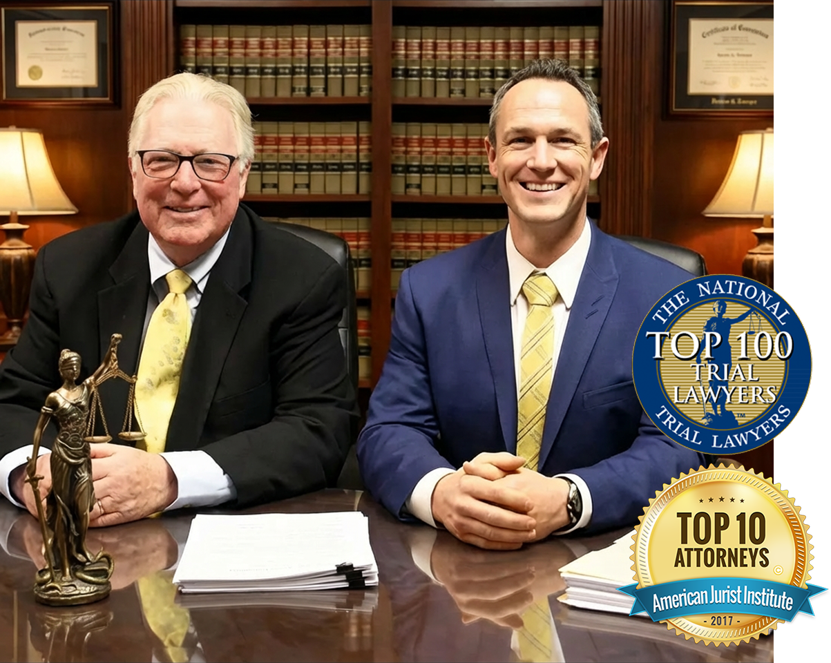 Frederick R. Dunne, Jr. and F.R. ‘Chip’ Dunne, III seated at a desk in a law office, with legal books and awards in the background.