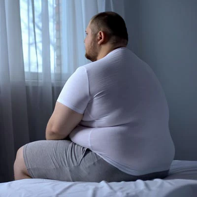 Overweight man sitting on a bed