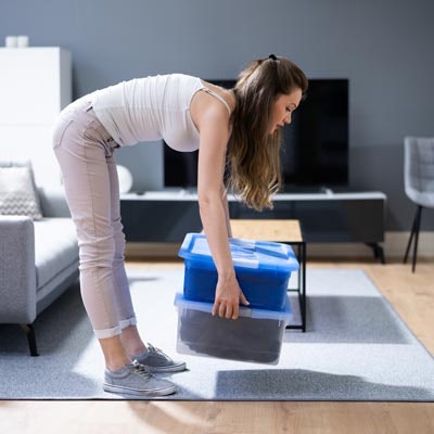 Woman lifting boxes with her back while in standing position