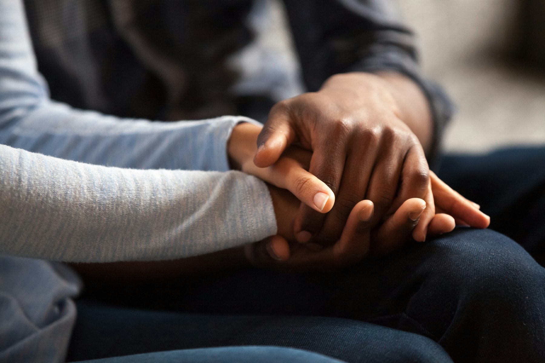 Two people holding hands in a consoling way