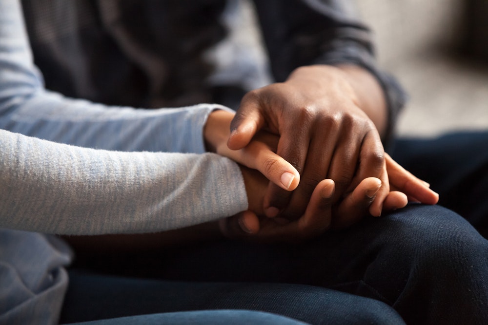 Two people holding hands in a consoling way