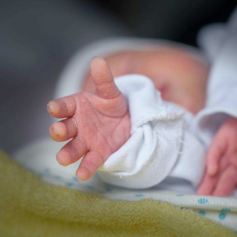Baby lying down reaching out hand