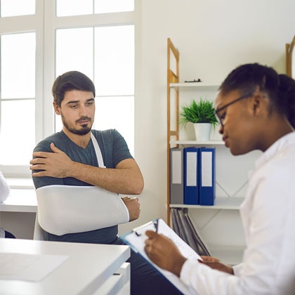 Man in sling talking to doctor