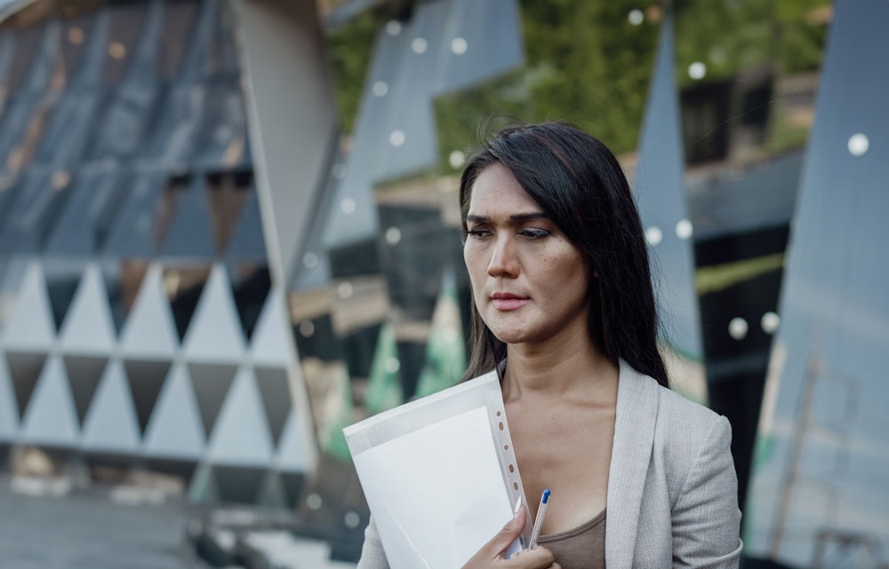 Transgender woman looking sad walking out of an office building