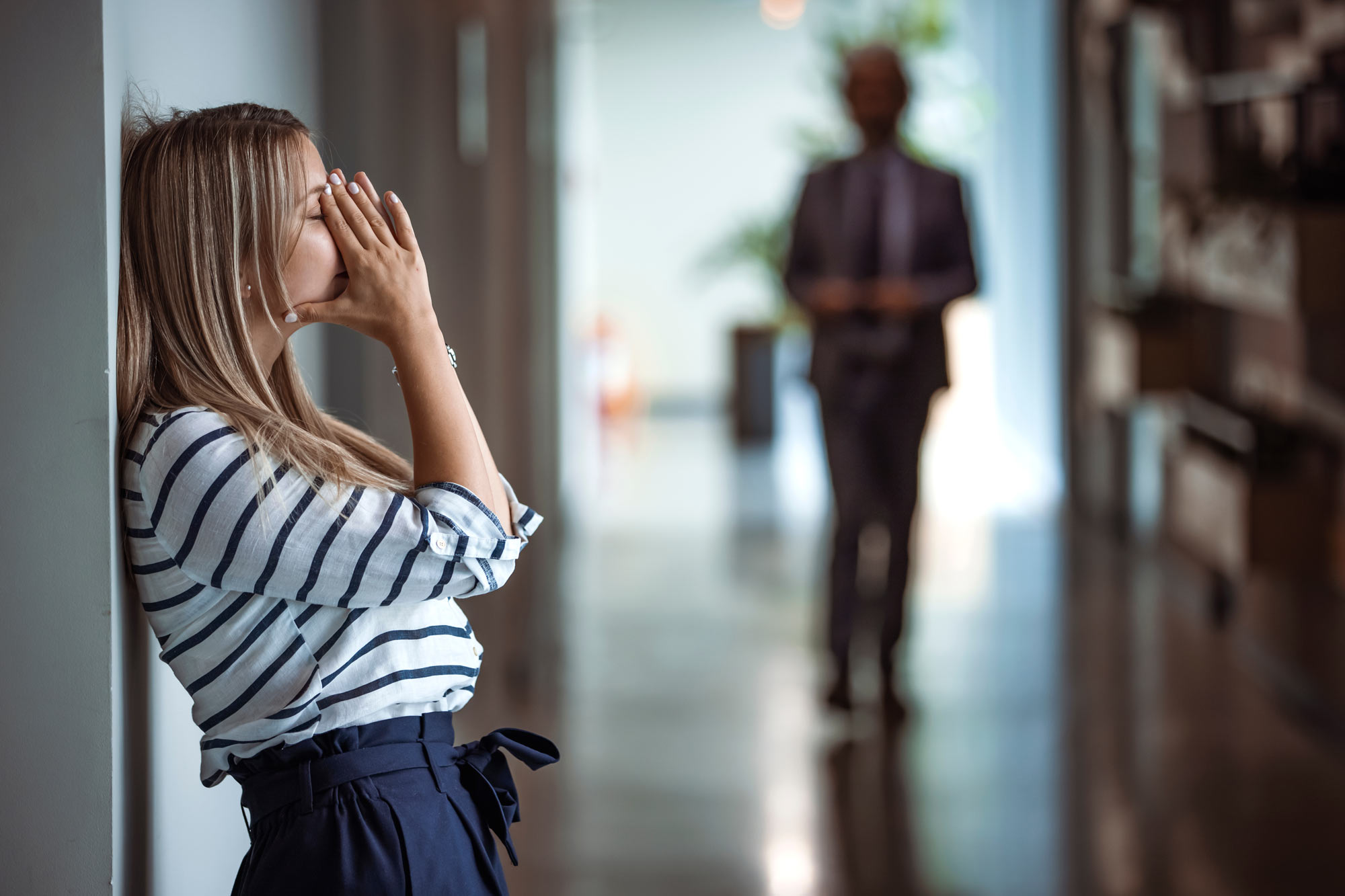 Woman breathing into hands in hallway