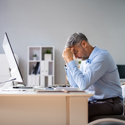 Middle aged worker with heads in hands