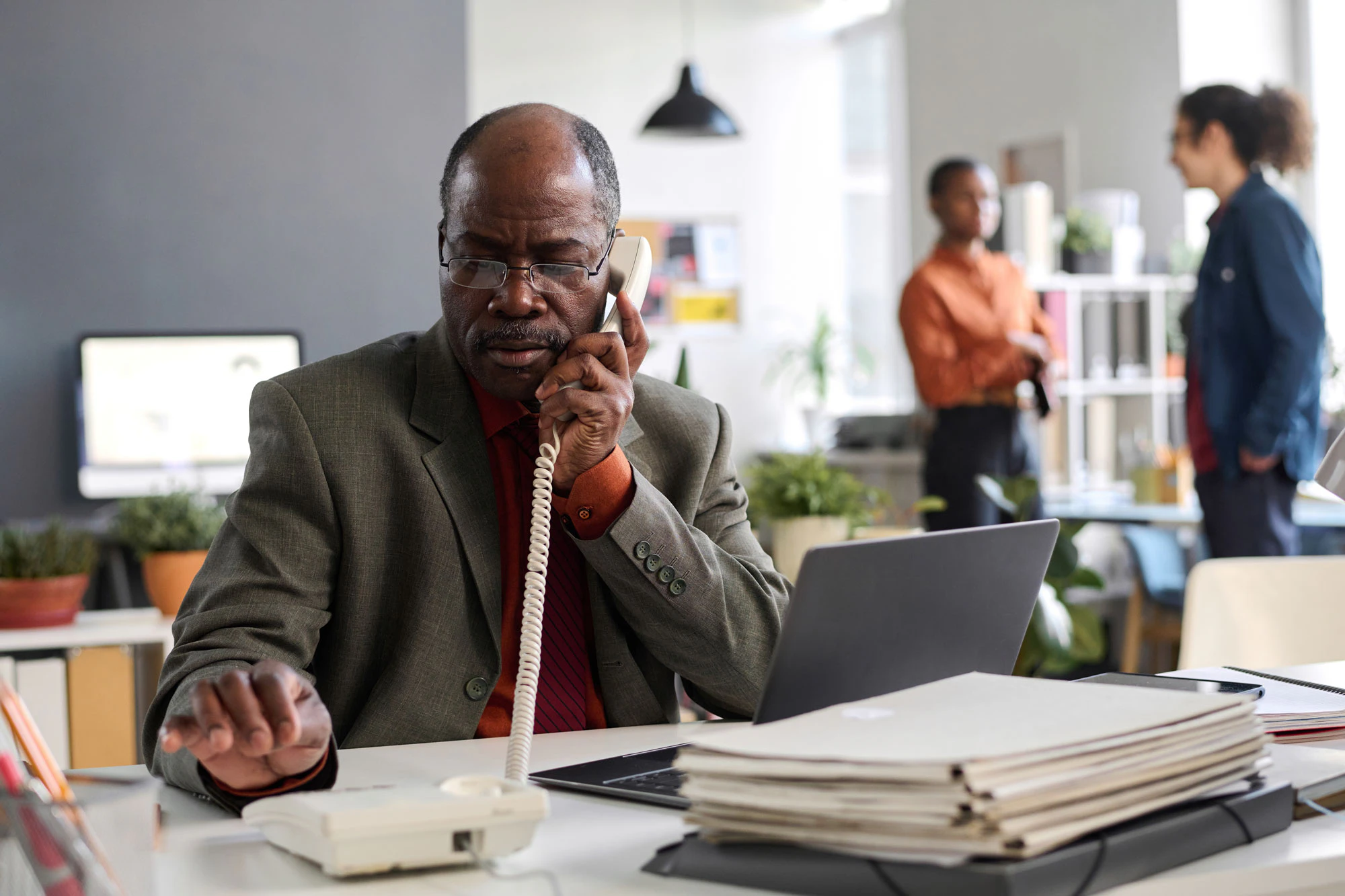 Man on the phone at workplace with coworkers in the background