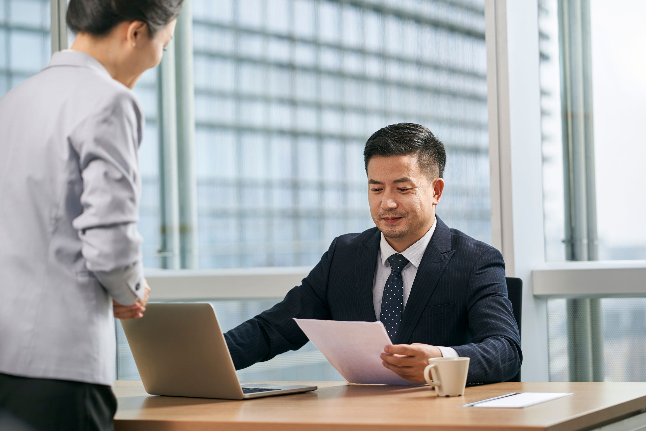 Man at a computer reviewing paperwork