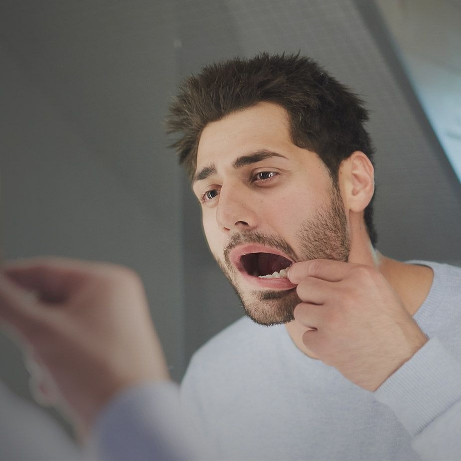 Man inspecting teeth in mirror