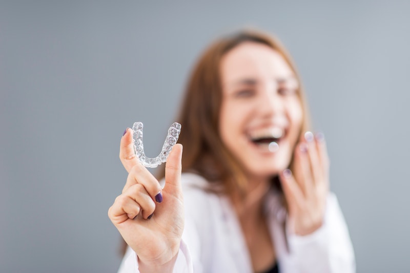 a woman holding an Invisalign aligner