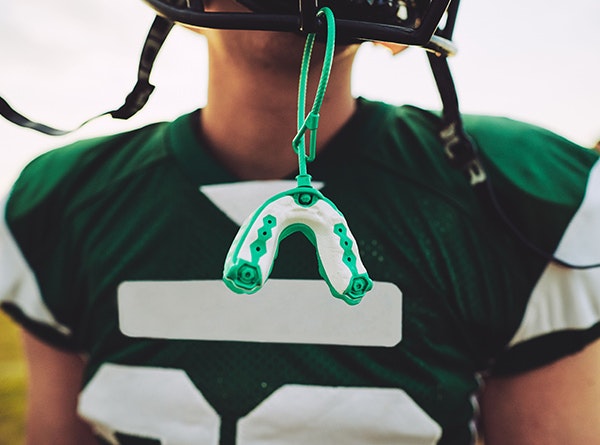 Football player with tooth guard attached to helmet