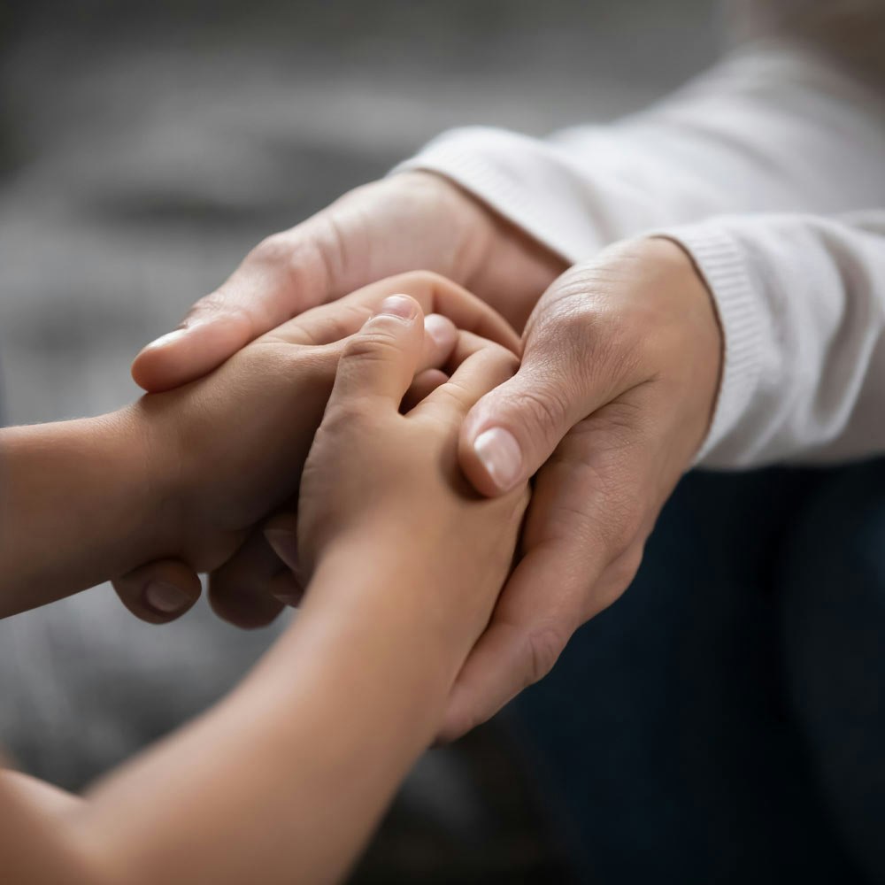 Close-up of a child's hand with adult hands