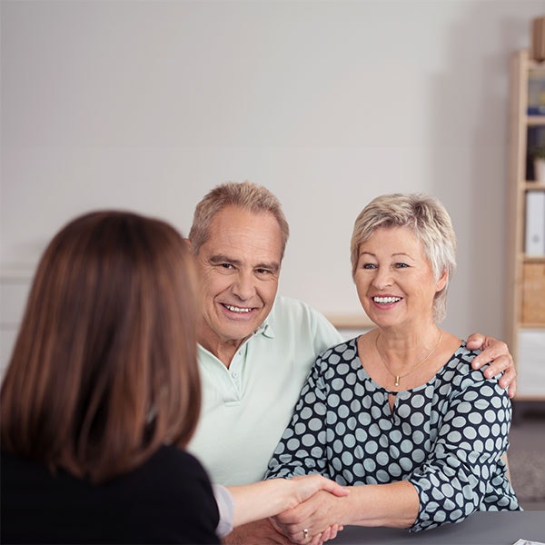Elderly couple shaking hands with lawyer